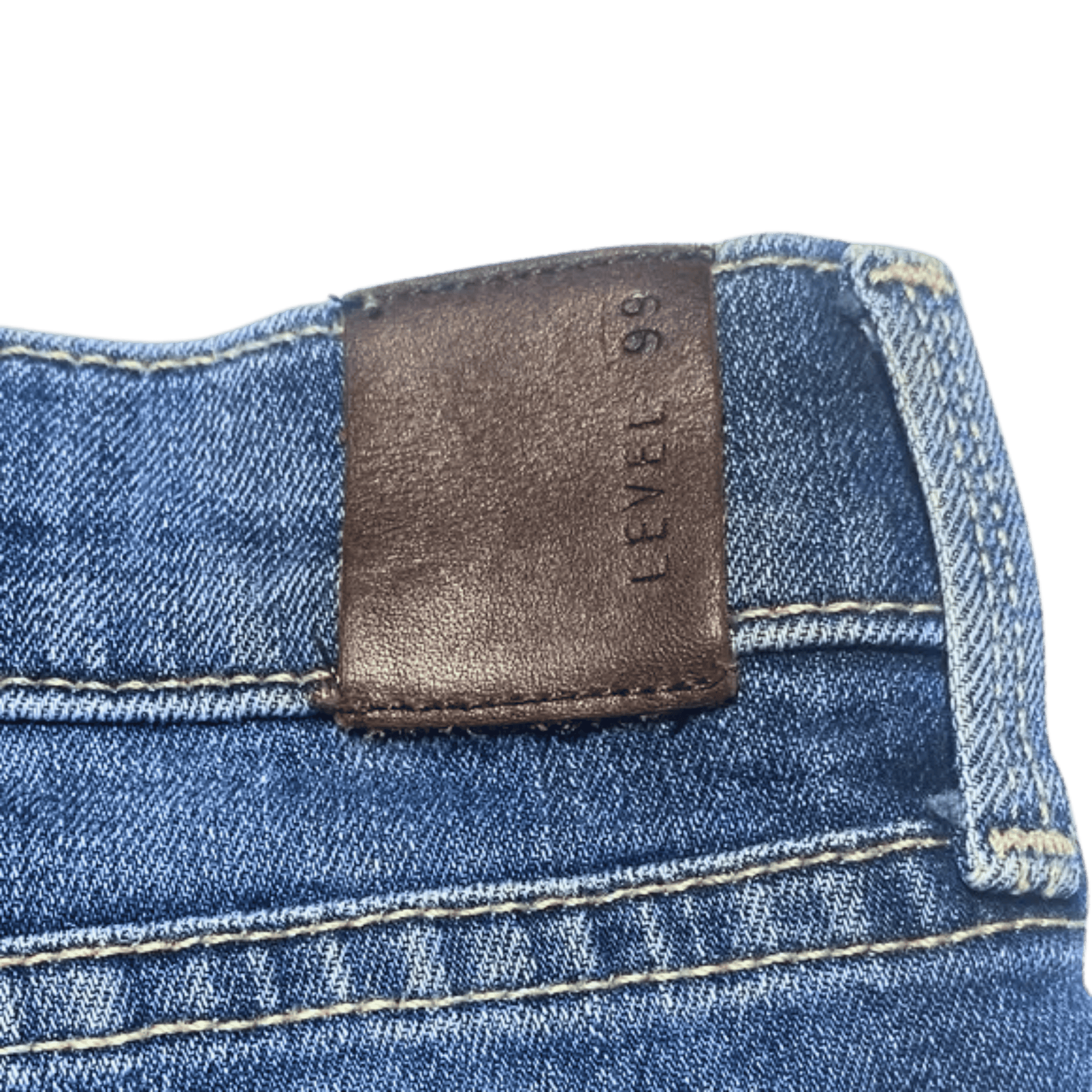 Close-up of a blue denim fabric with a brown leather label on a green background