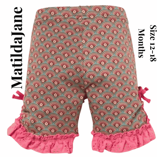 Patterned baby pants with ruffles on a pink background, featuring the brand 'Matilda Jane'.