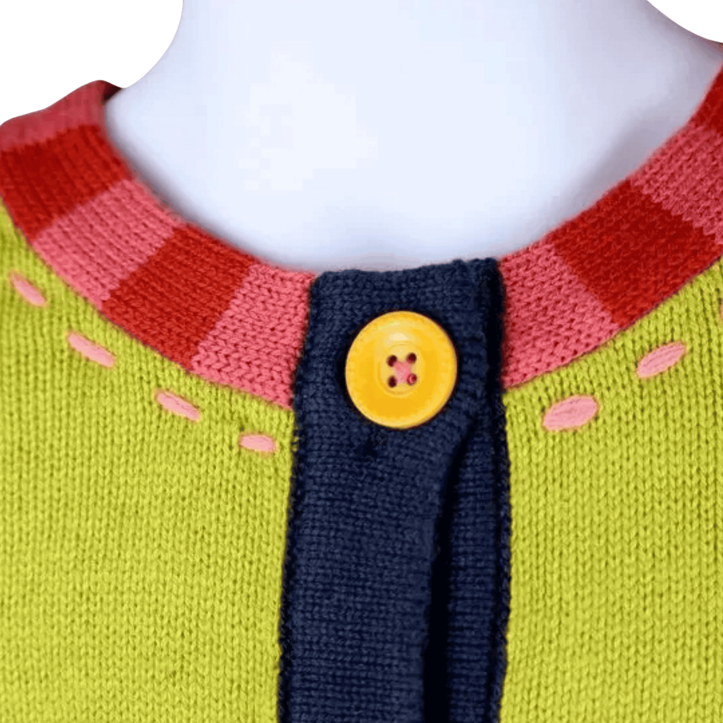 Close-up of a colorful knitted sweater with a yellow button on a mannequin.