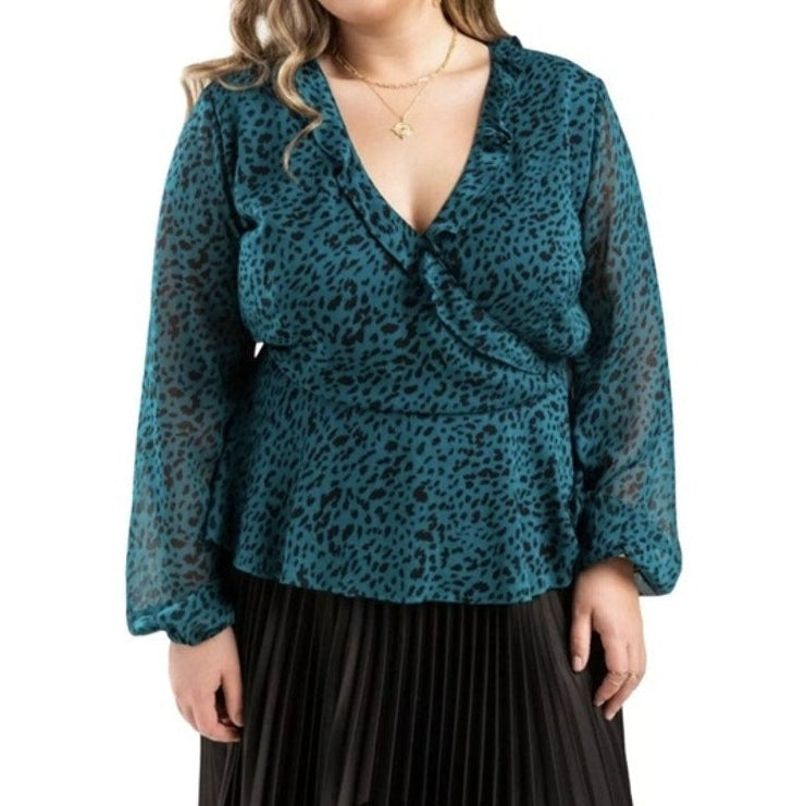 Teal leopard print blouse worn by a person on a white background