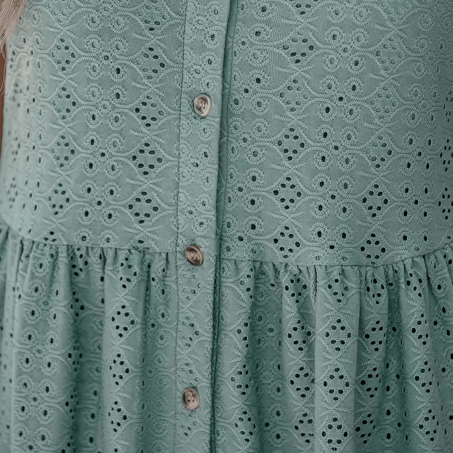 Green dress with lace detailing and buttons on a plain background