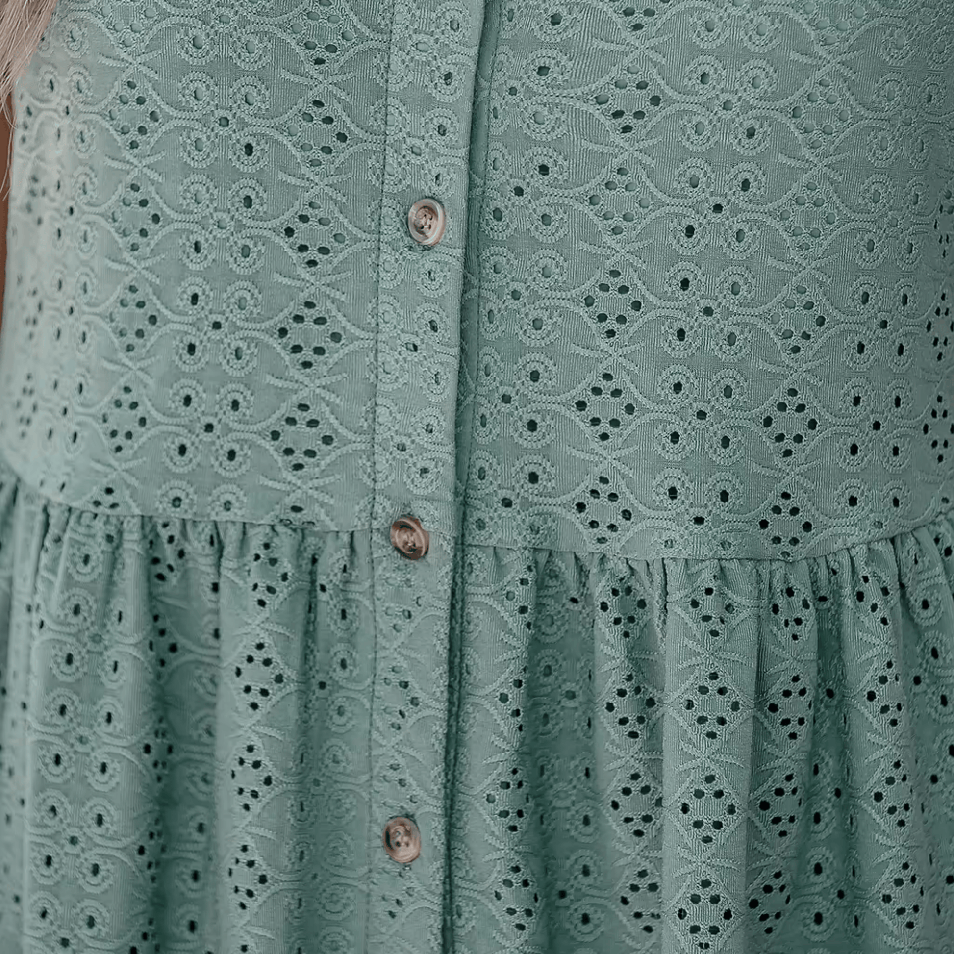 Green dress with lace detailing and buttons on a plain background