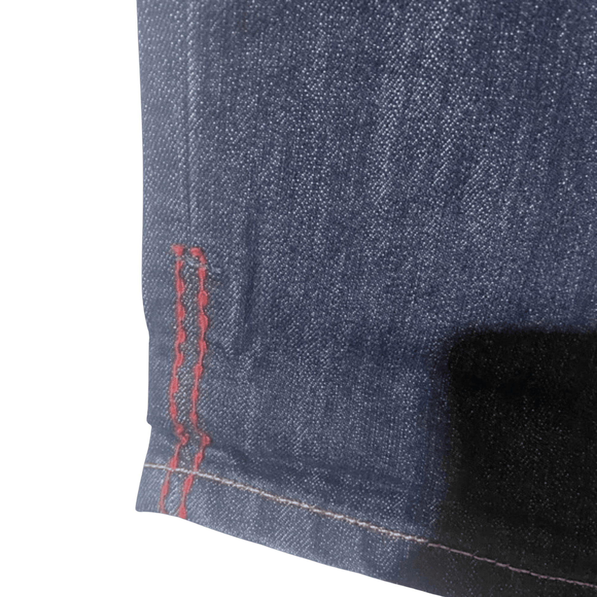 Close-up of blue denim fabric with red stitching on a green background