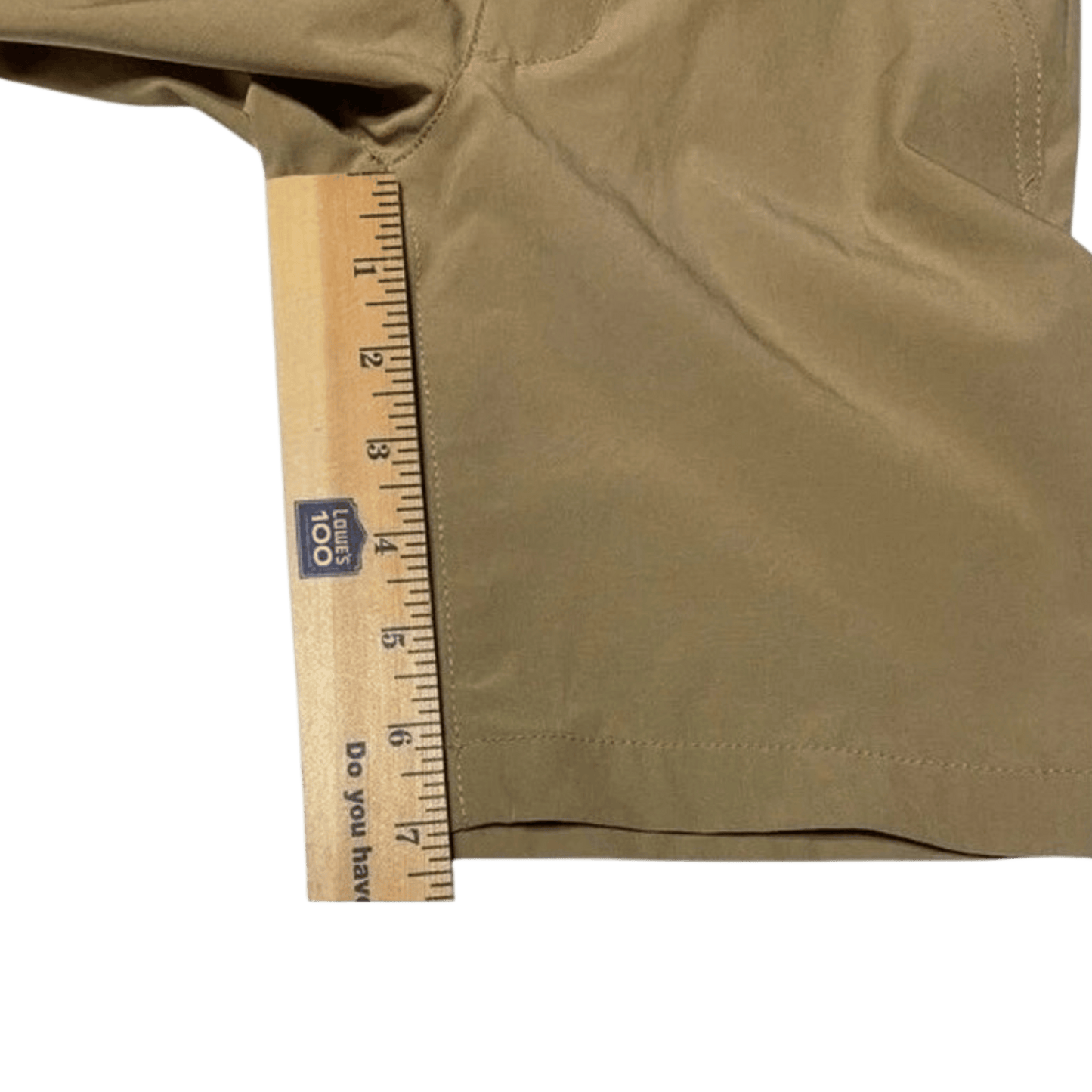 Brown shorts with a wooden ruler for size reference on a green background