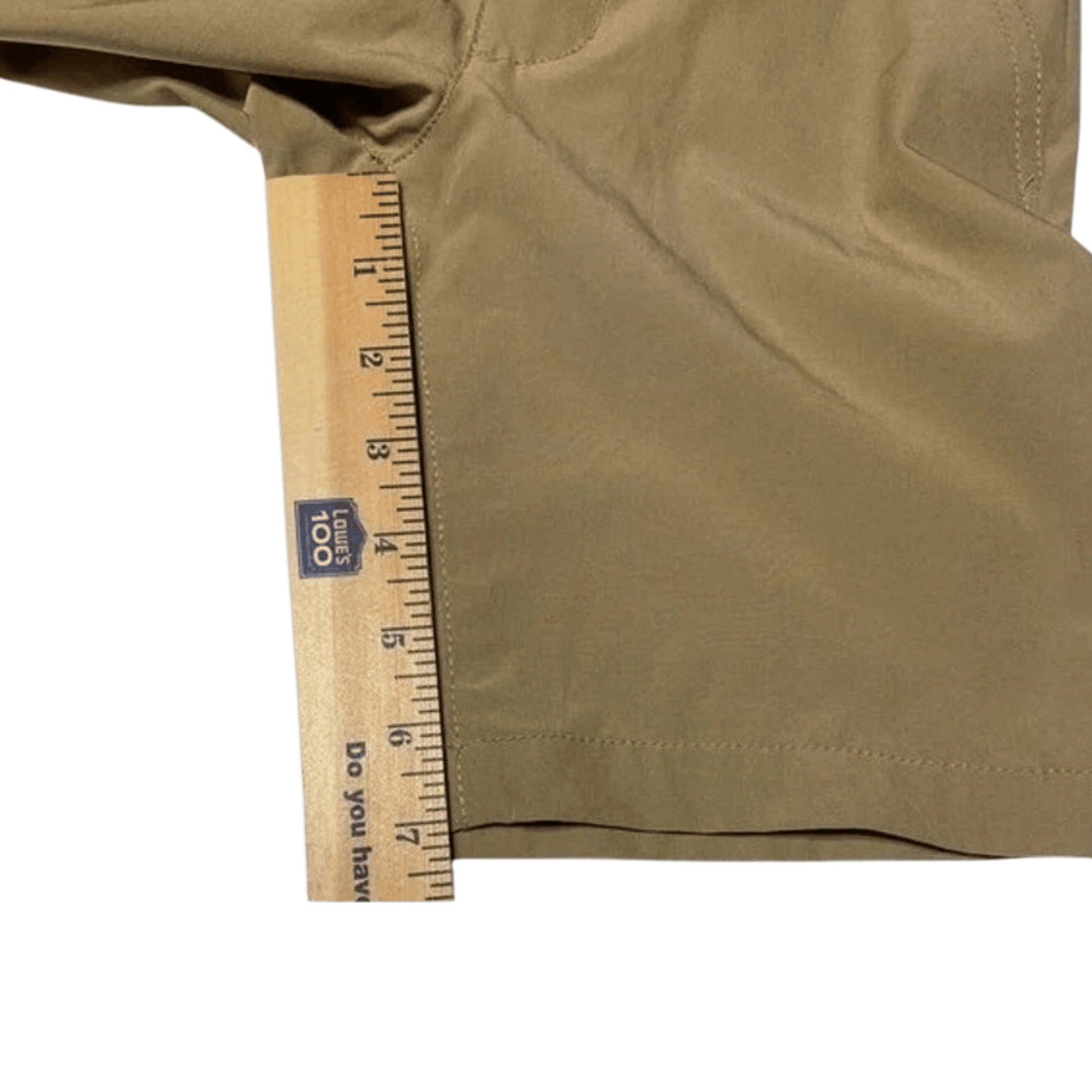 Brown shorts with a wooden ruler for size reference on a green background
