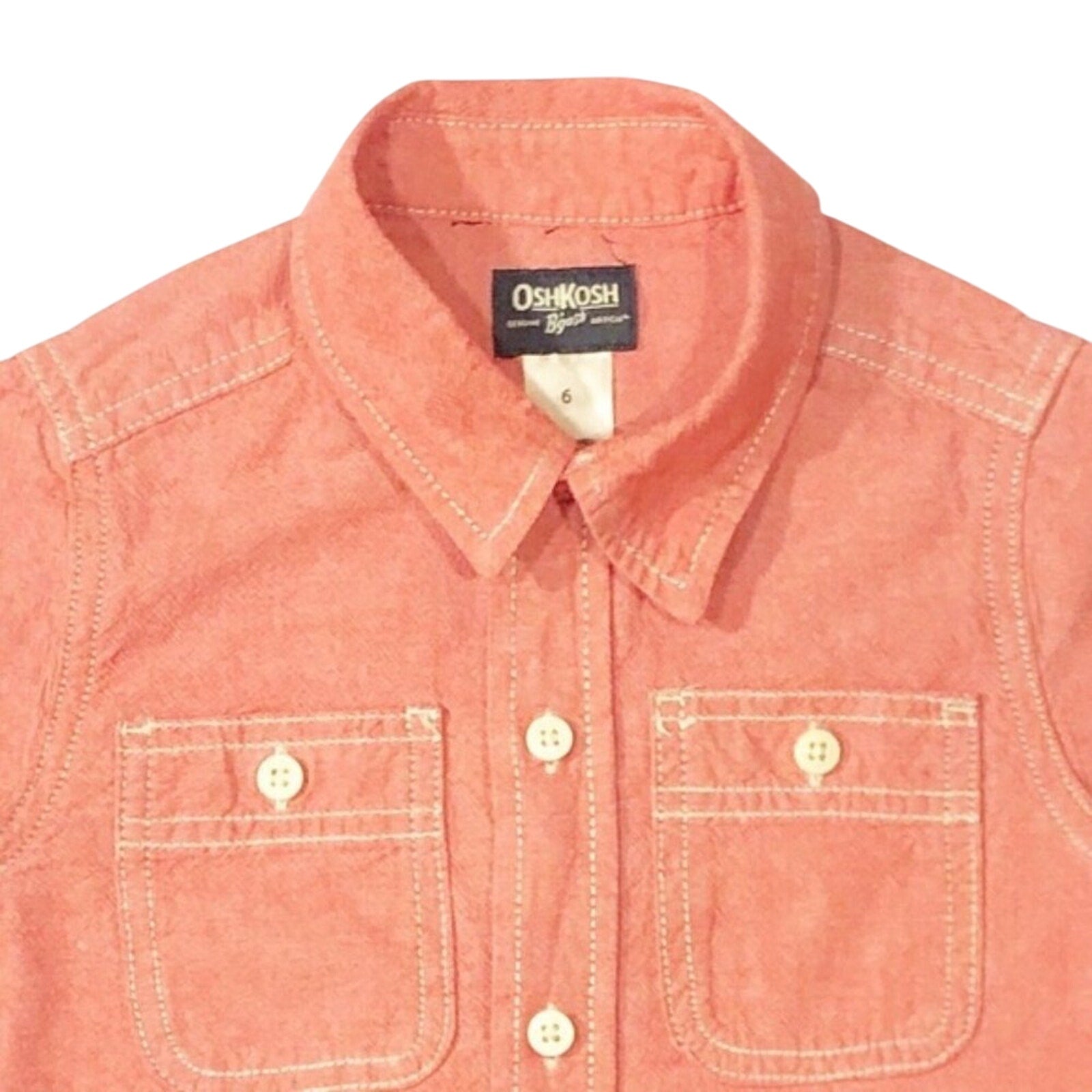 Close-up of a coral-colored shirt with a collar and OshKosh label.