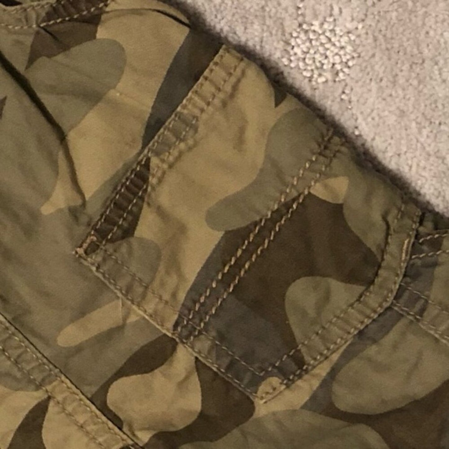 Close-up of a camouflage-patterned fabric with stitching details.