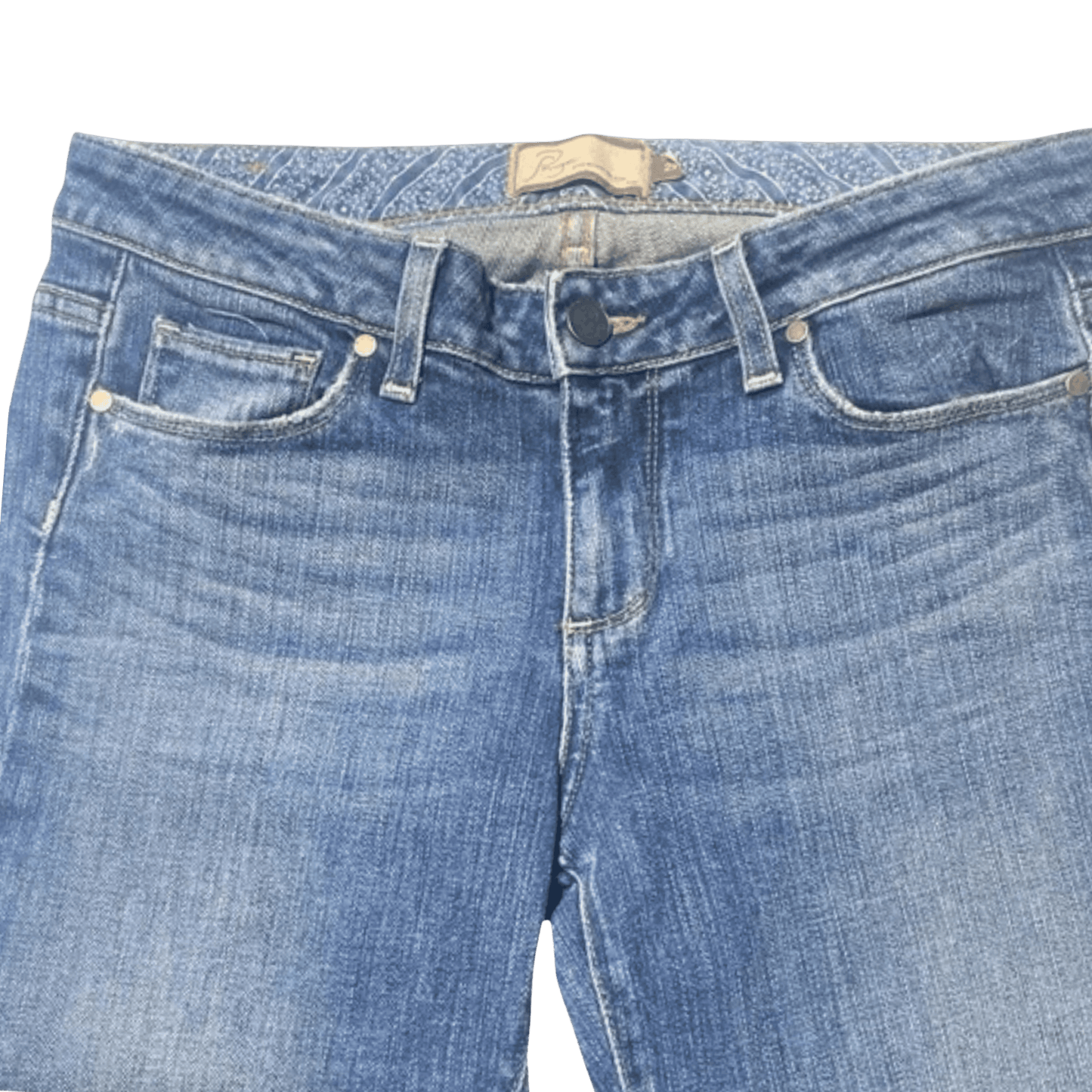 Close-up of blue jeans with a brand label on a green background