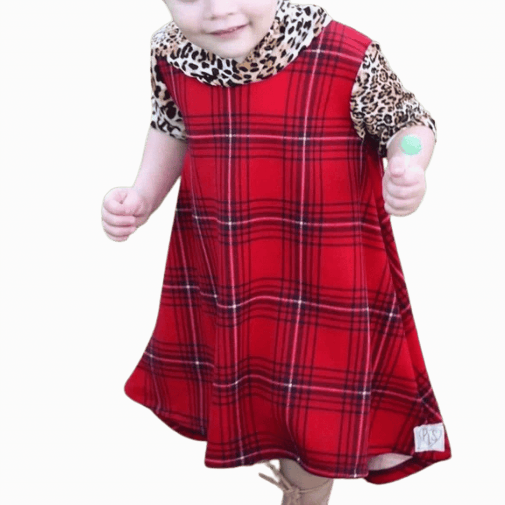 Child wearing a red plaid dress with leopard print sleeves on a brown background