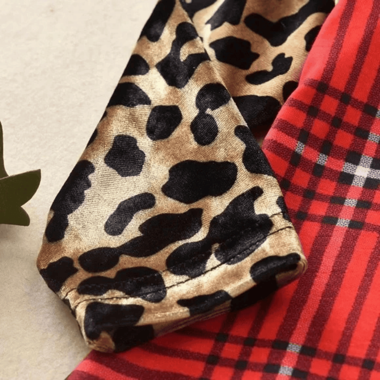 Leopard print fabric and red plaid fabric on a neutral background