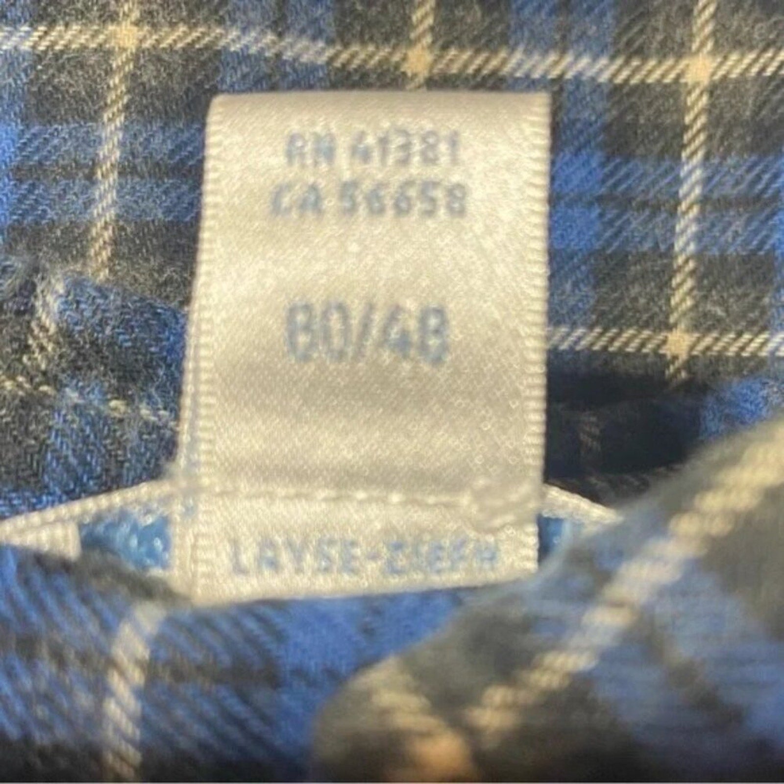Label on a blue and black plaid fabric with text and numbers.