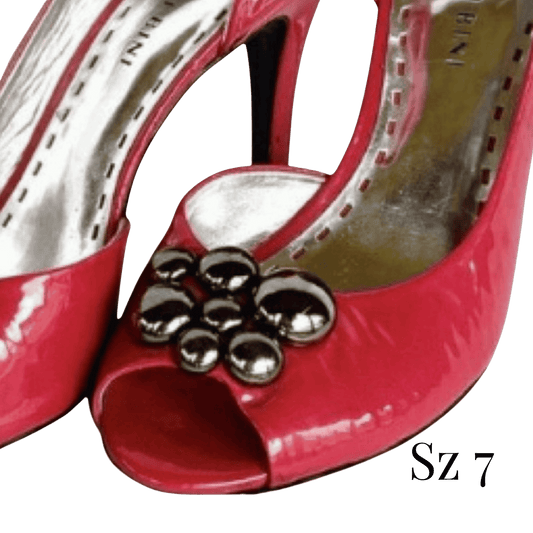 Red high-heeled shoe with decorative embellishments on a clear background