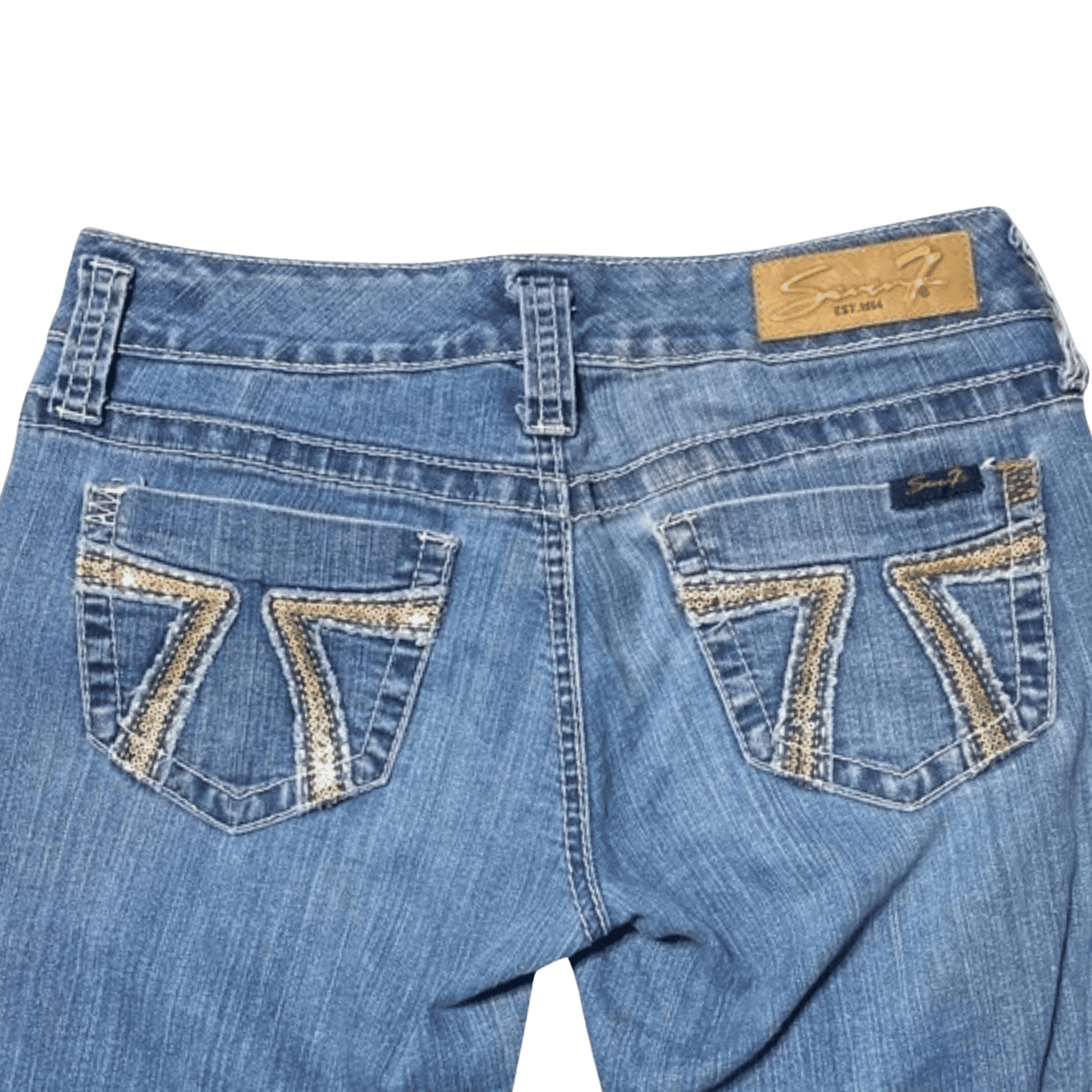 Blue jeans with decorative stitching on the back pockets against a green background