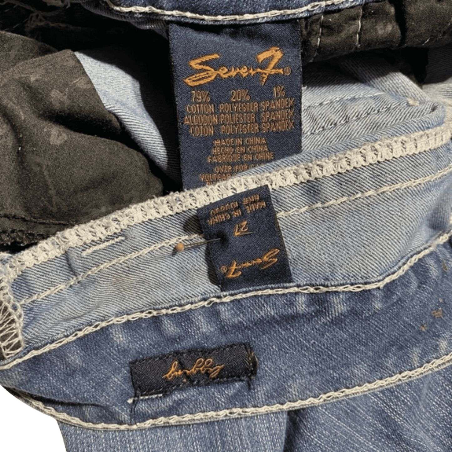 Close-up of Seven7 jeans with brand labels on a dark background