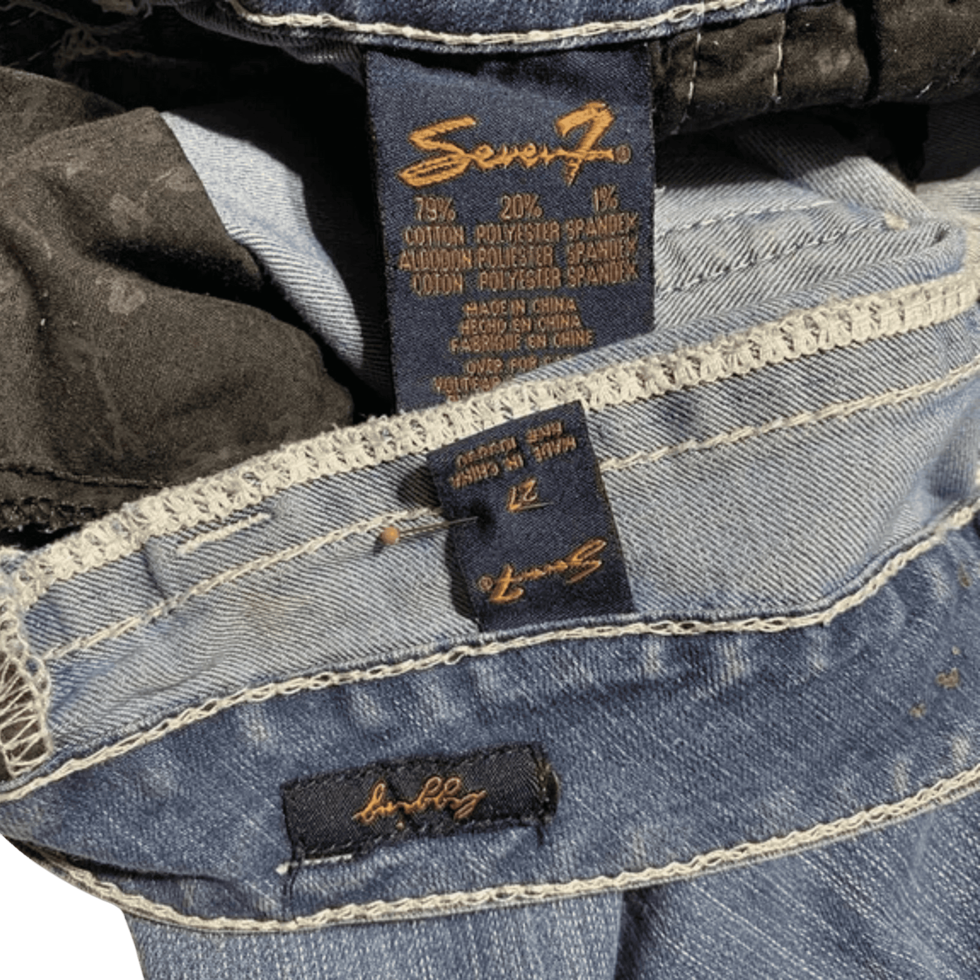 Close-up of Seven7 jeans with brand labels on a dark background
