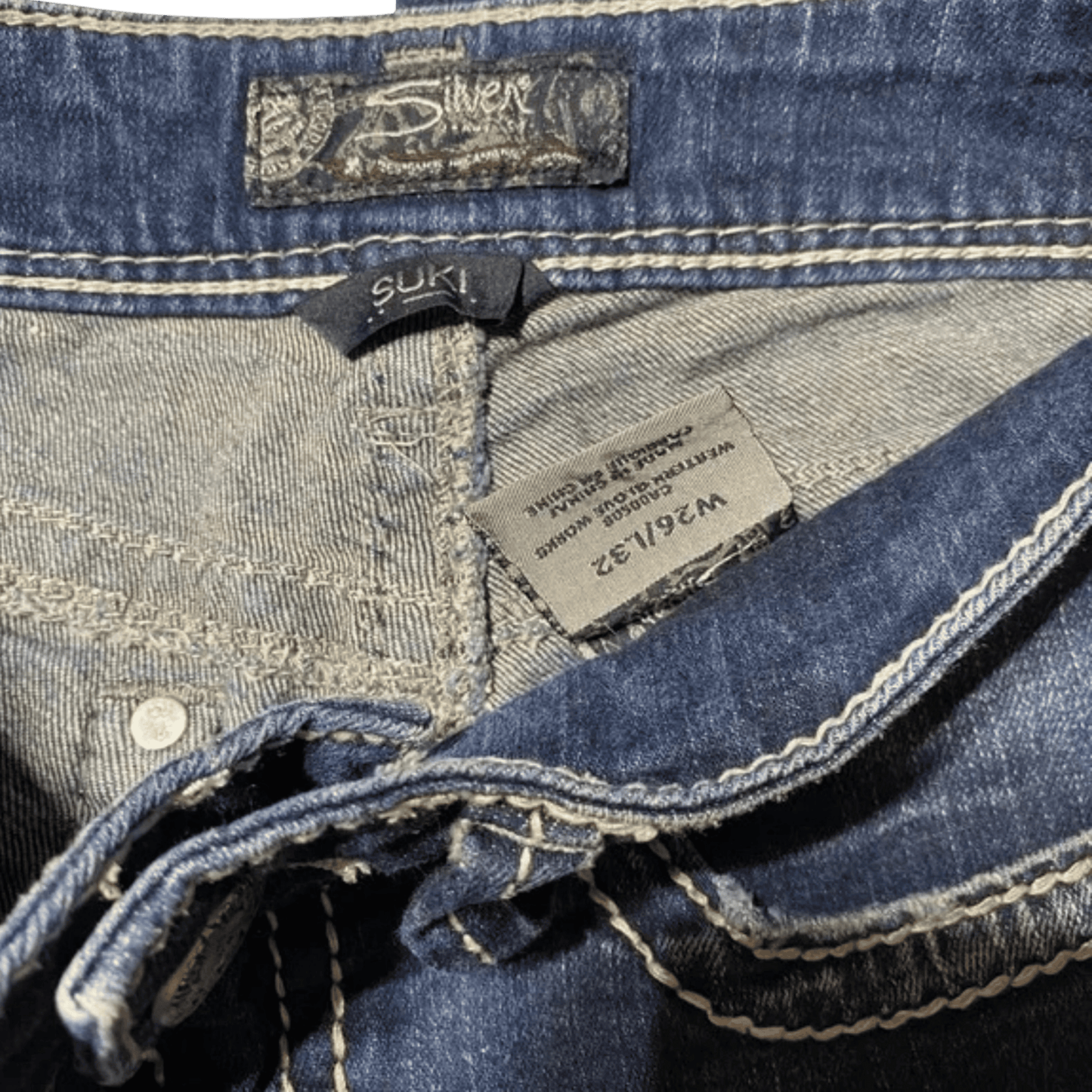 Close-up of blue denim jeans with brand labels and stitching details.