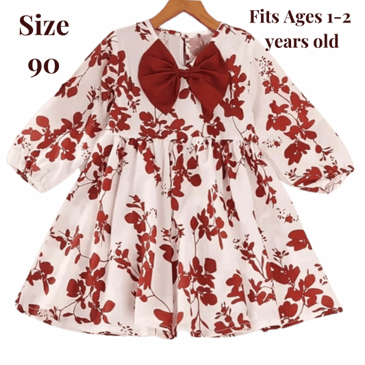 Floral dress with a red bow on a hanger against a green background