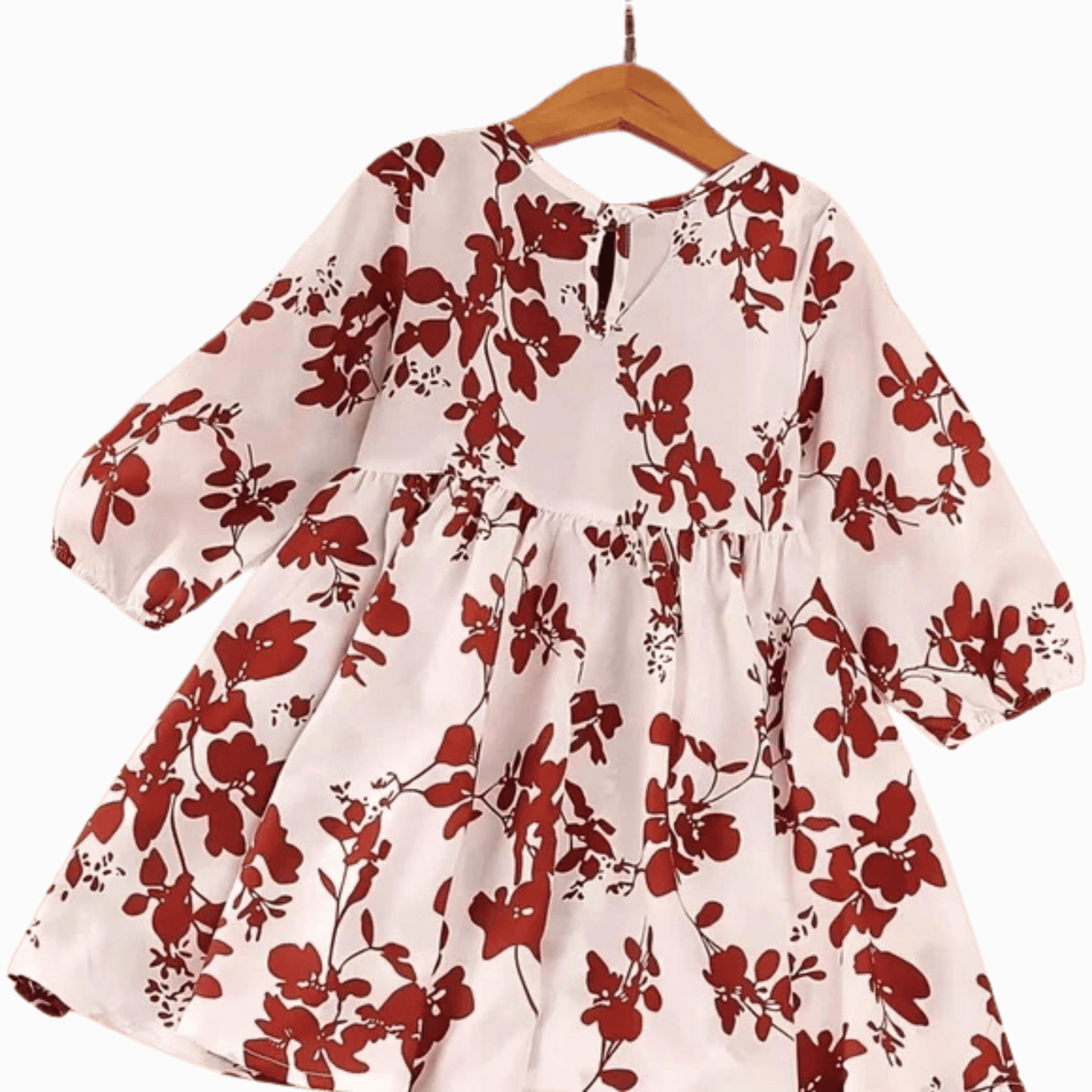 White dress with red floral pattern on a hanger against a brown background