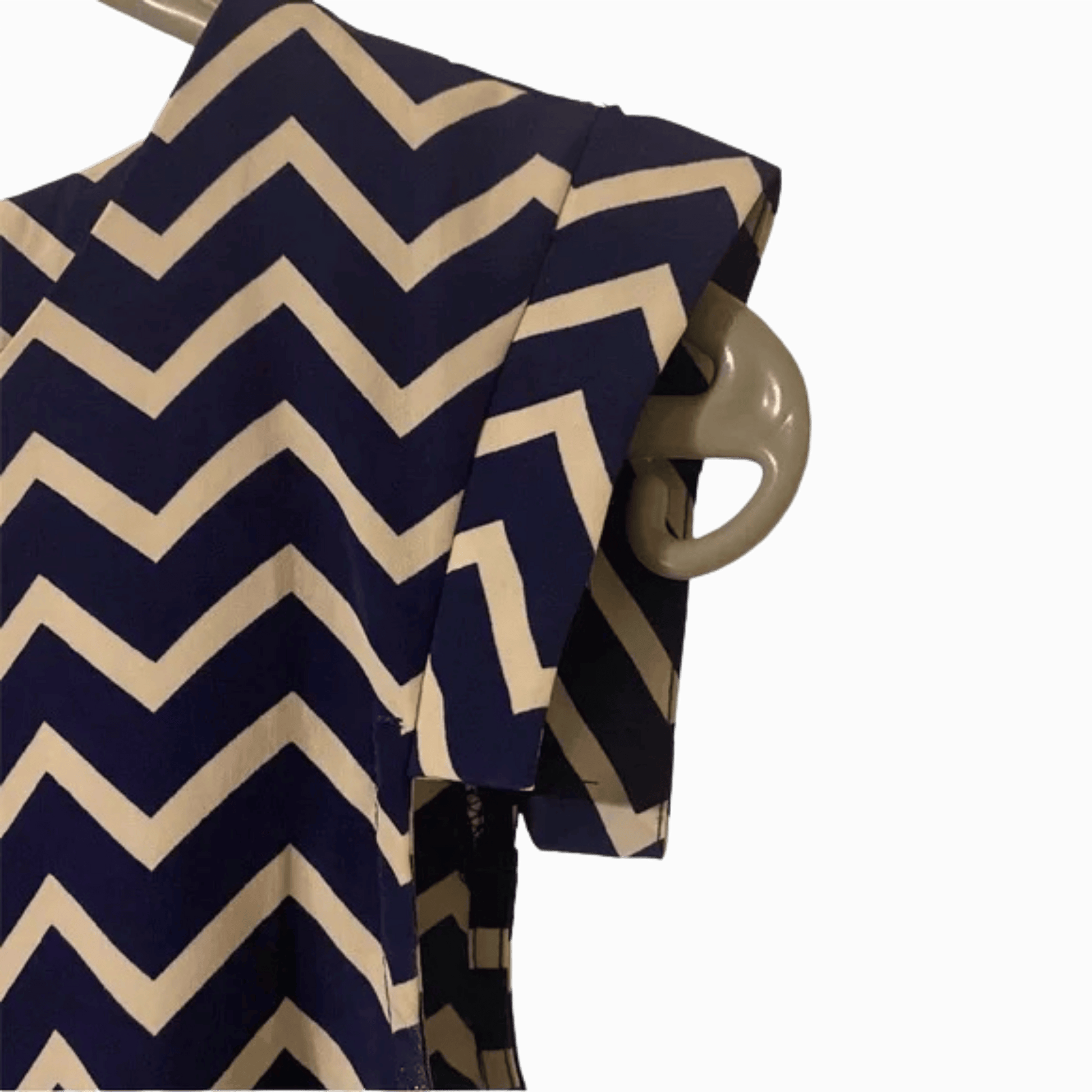 Navy and beige chevron patterned shirt on a hanger against a dark background