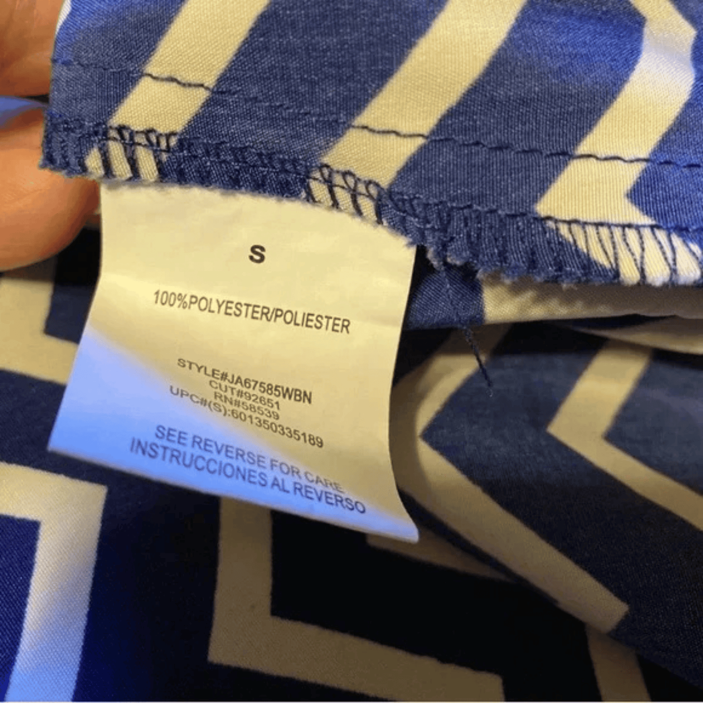 Close-up of a blue and beige striped fabric with a label showing 'S' size and material details.