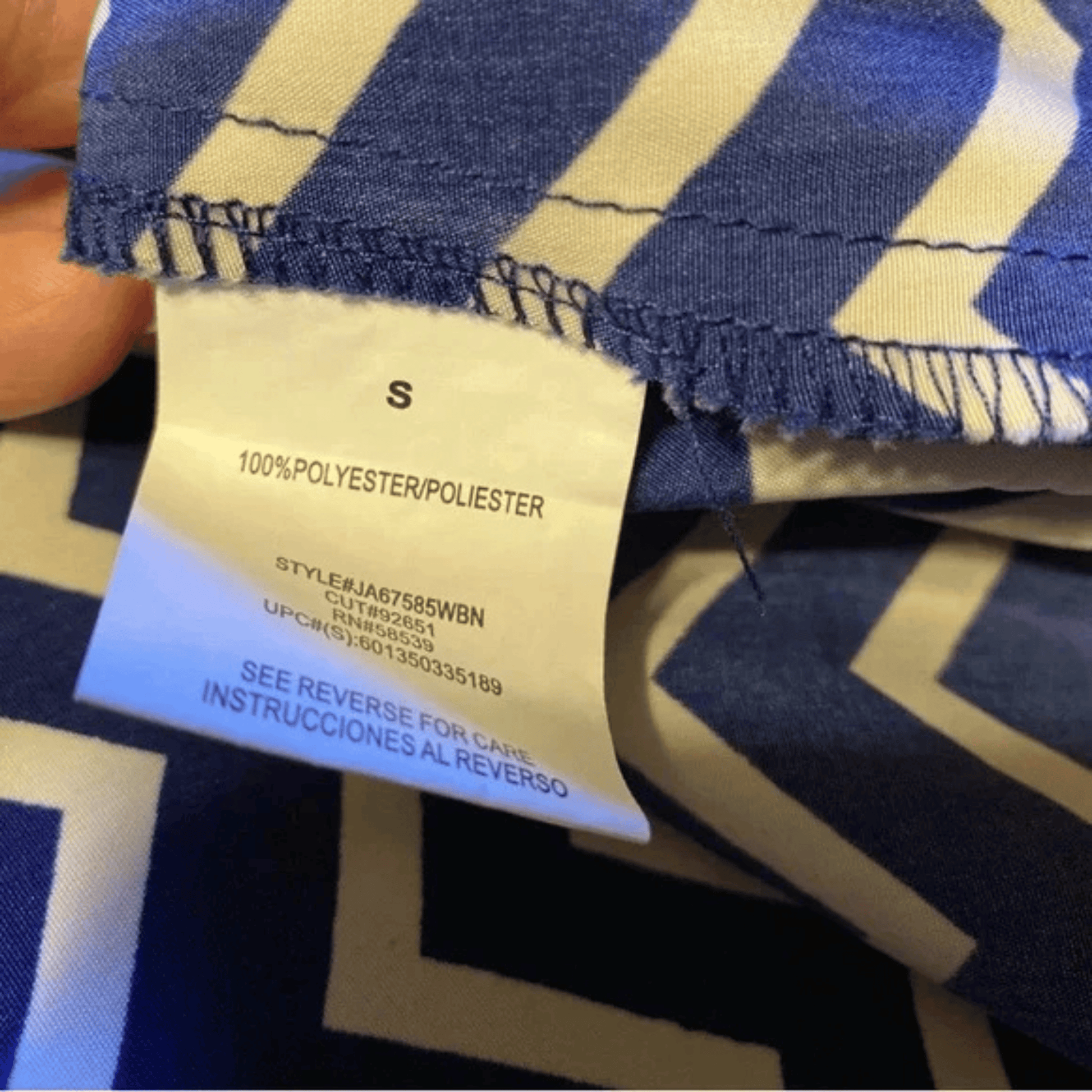 Close-up of a blue and beige striped fabric with a label showing 'S' size and material details.