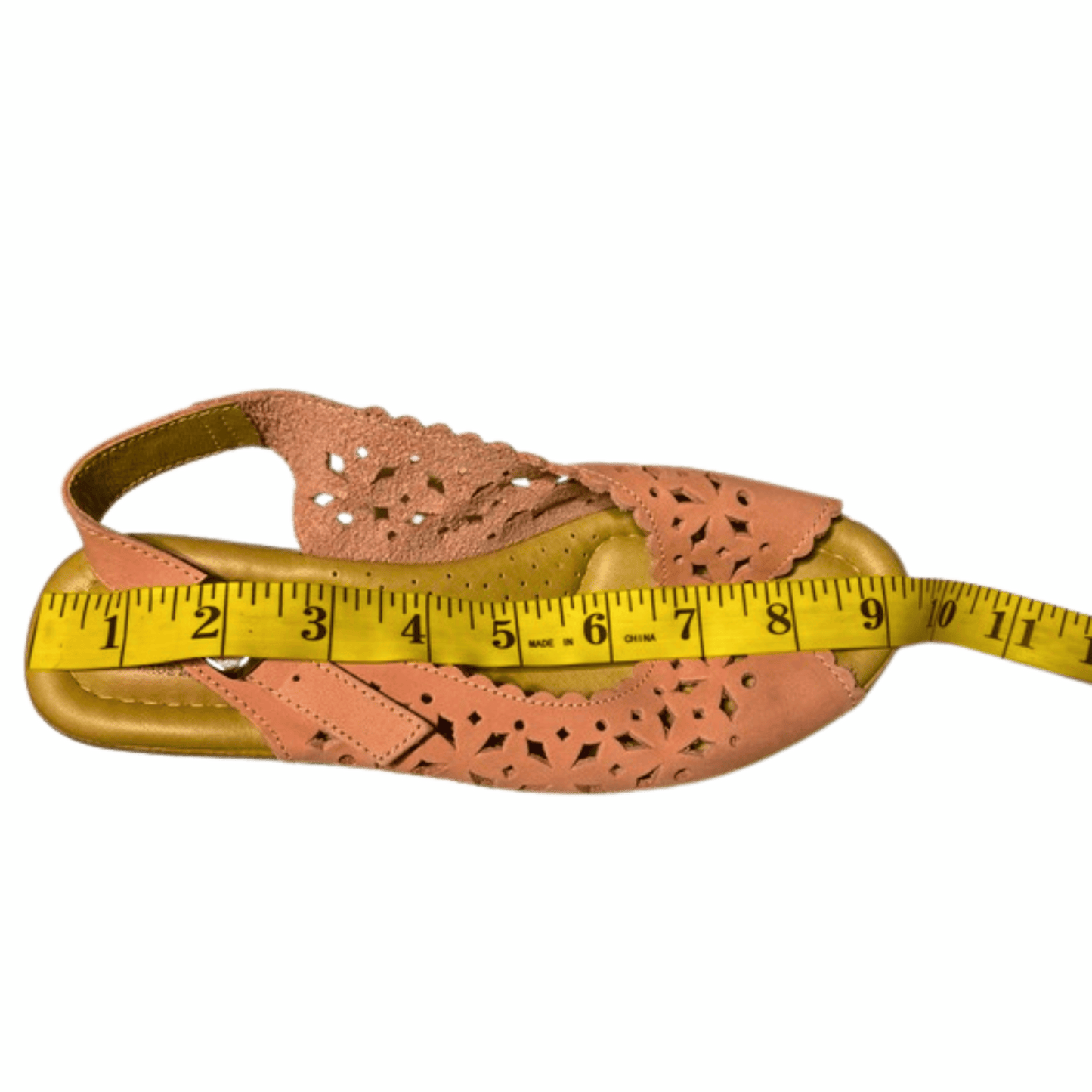 Pink sandal with a yellow measuring tape on a green background