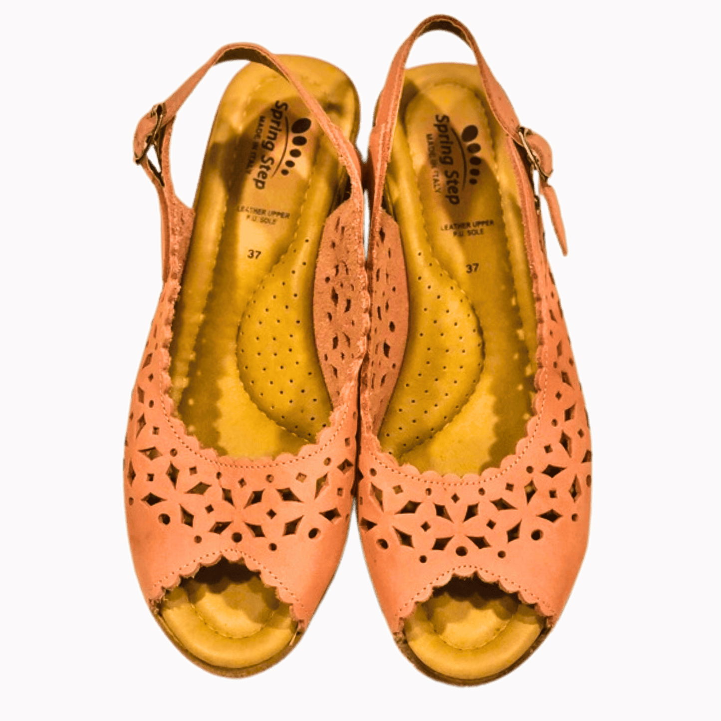 Pair of pink open-toe shoes with cut-out design on a brown background