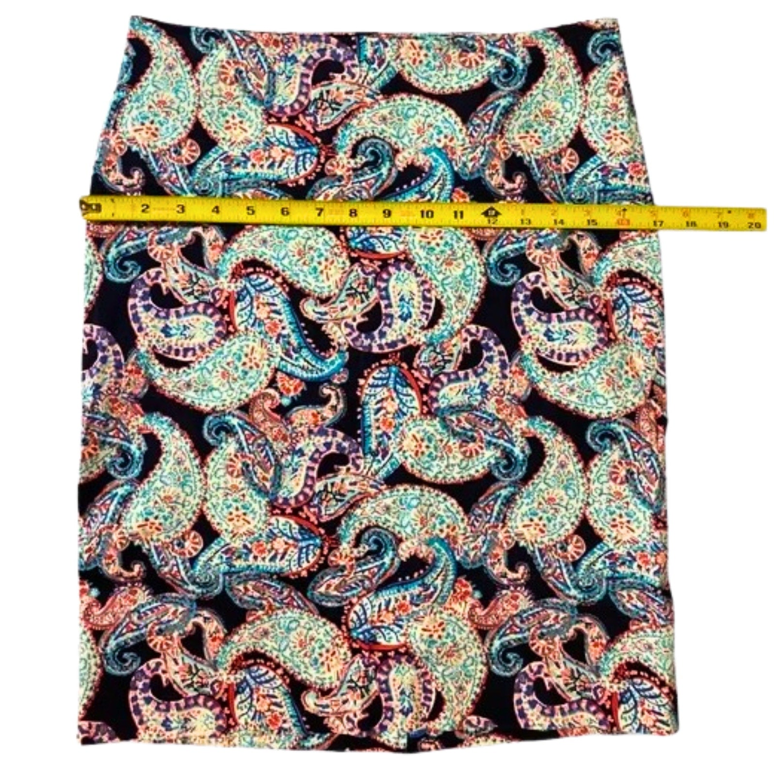 Paisley patterned fabric with a measuring tape on a white background