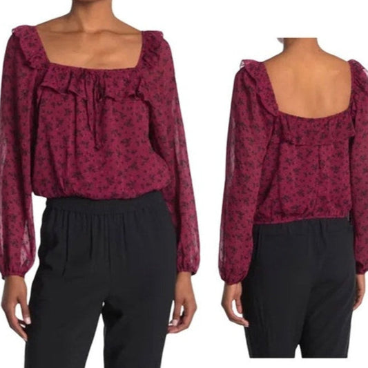 Red floral blouse with long sleeves and black pants on a white background