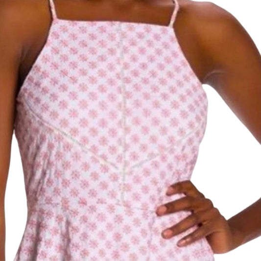 Woman wearing a pink floral dress with thin straps on a white background