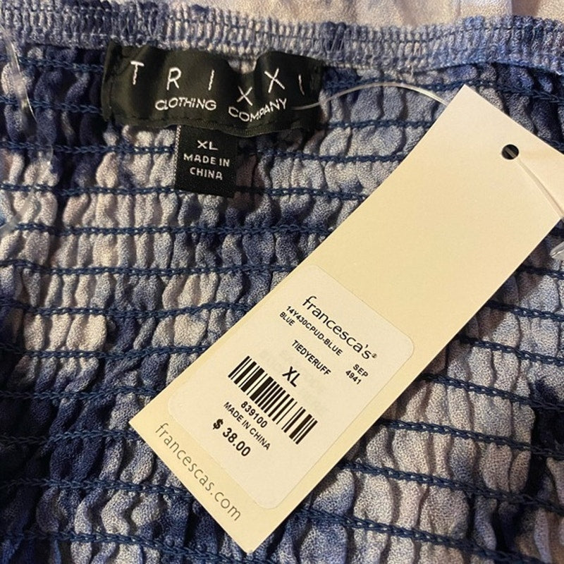 Clothing tag with 'Trixi' brand name and 'Francesca's' label on a textured fabric background.