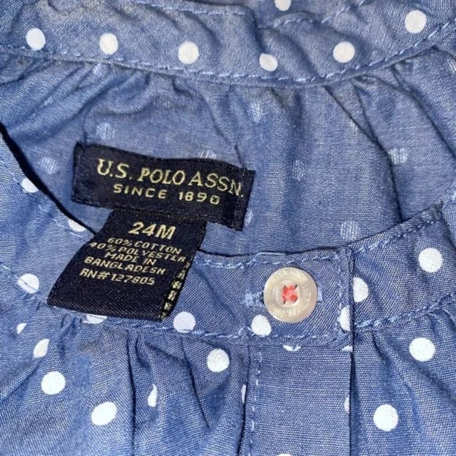 Close-up of U.S. Polo Assn. label on a blue polka dot shirt with a button.