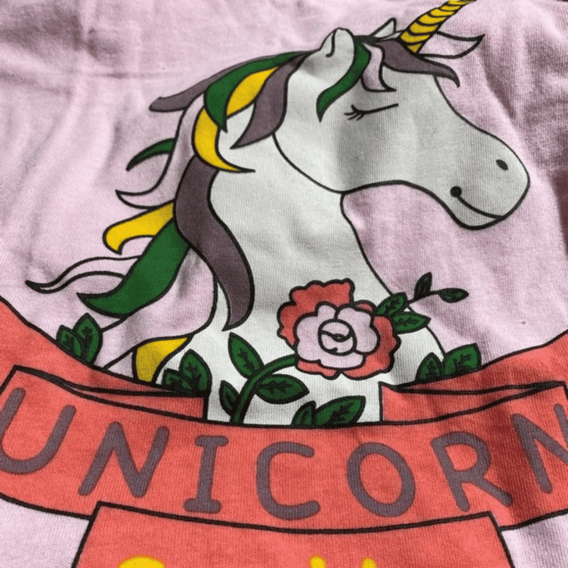 Unicorn design on a pink background with flowers and a banner