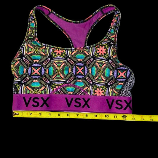 Colorful sports bra with geometric pattern and 'VSX' branding, accompanied by a measuring tape.