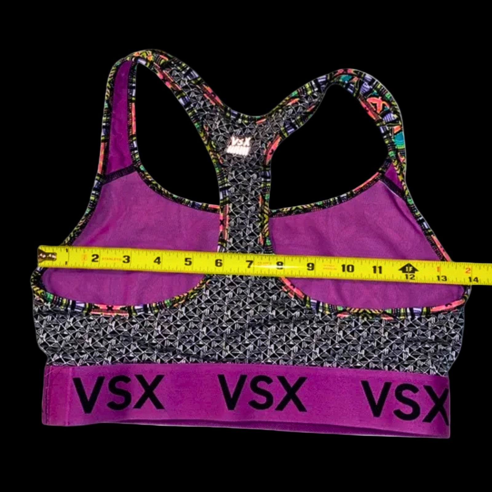 Purple sports bra with multicolor straps and 'VSX' branding, measured with a tape measure on a white background.