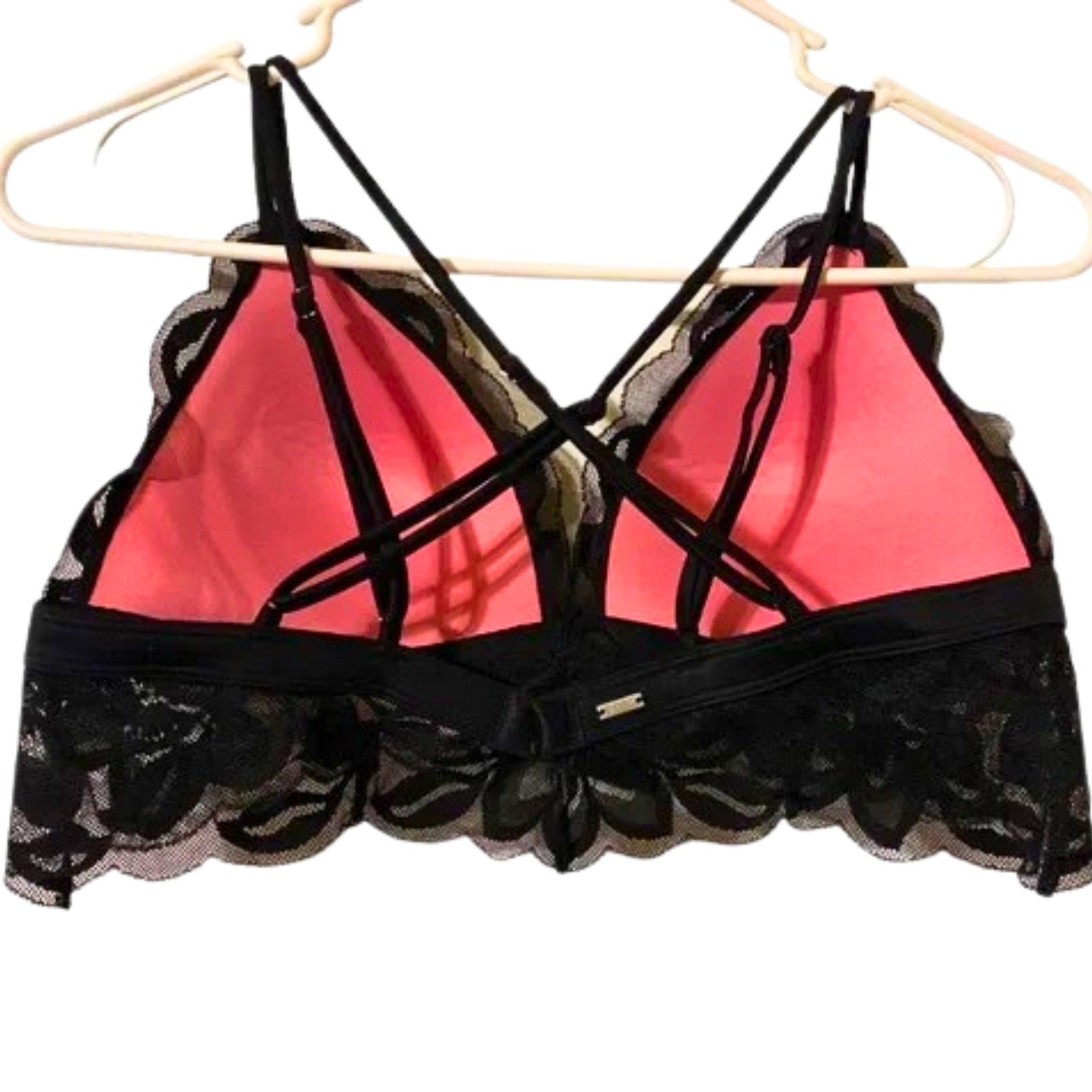 Black lace-trimmed bra with pink interior on a hanger against a white background