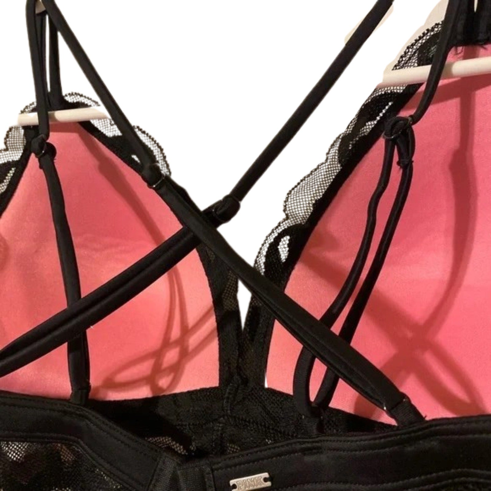 Black strappy top with pink lining on a white background