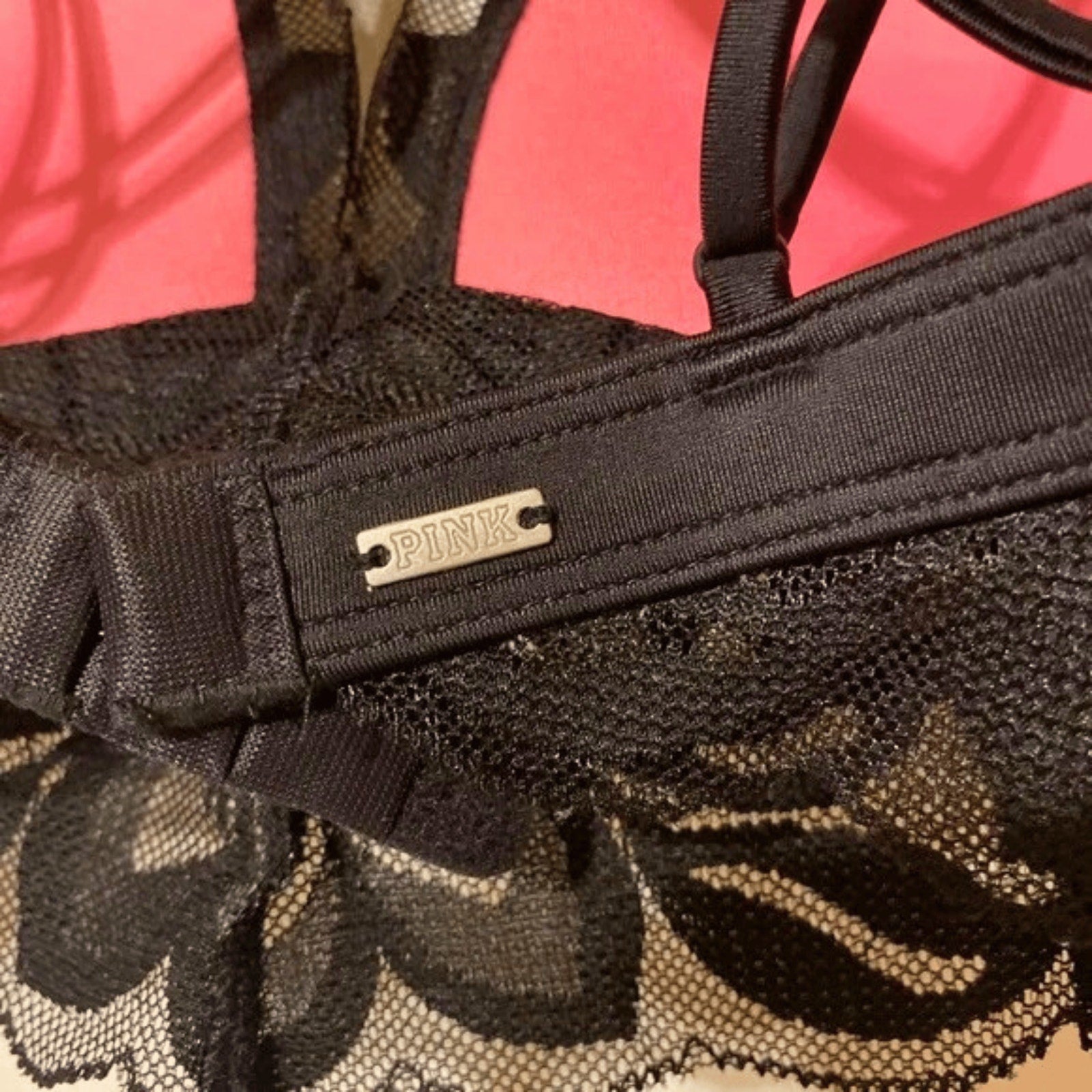 Close-up of a black lace garment with a 'PINK' label on a pink background