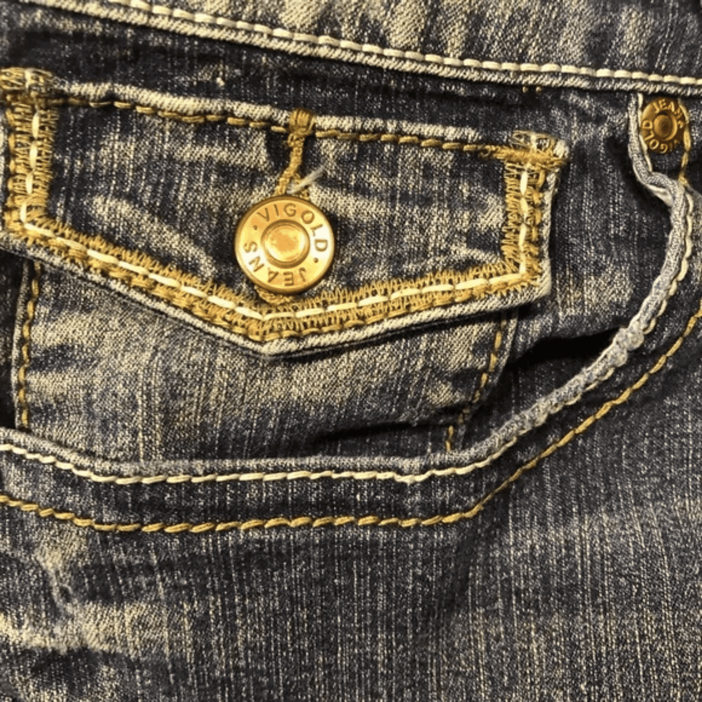 Close-up of a pocket on a denim jacket with a gold button and brand name.