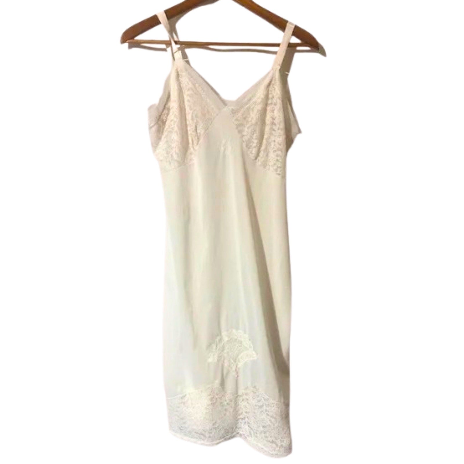 Cream-colored lace camisole on a wooden hanger against a white background