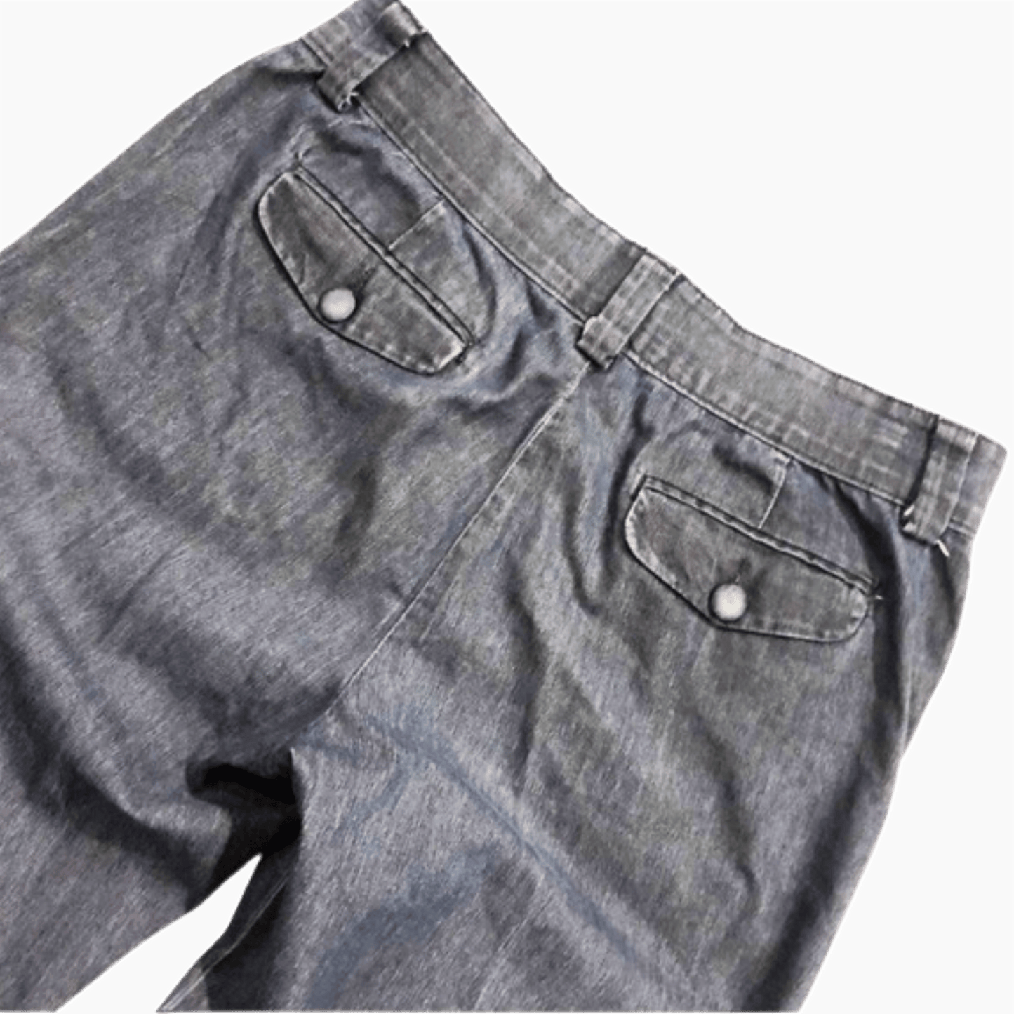Close-up of gray denim pants with button details on a dark background