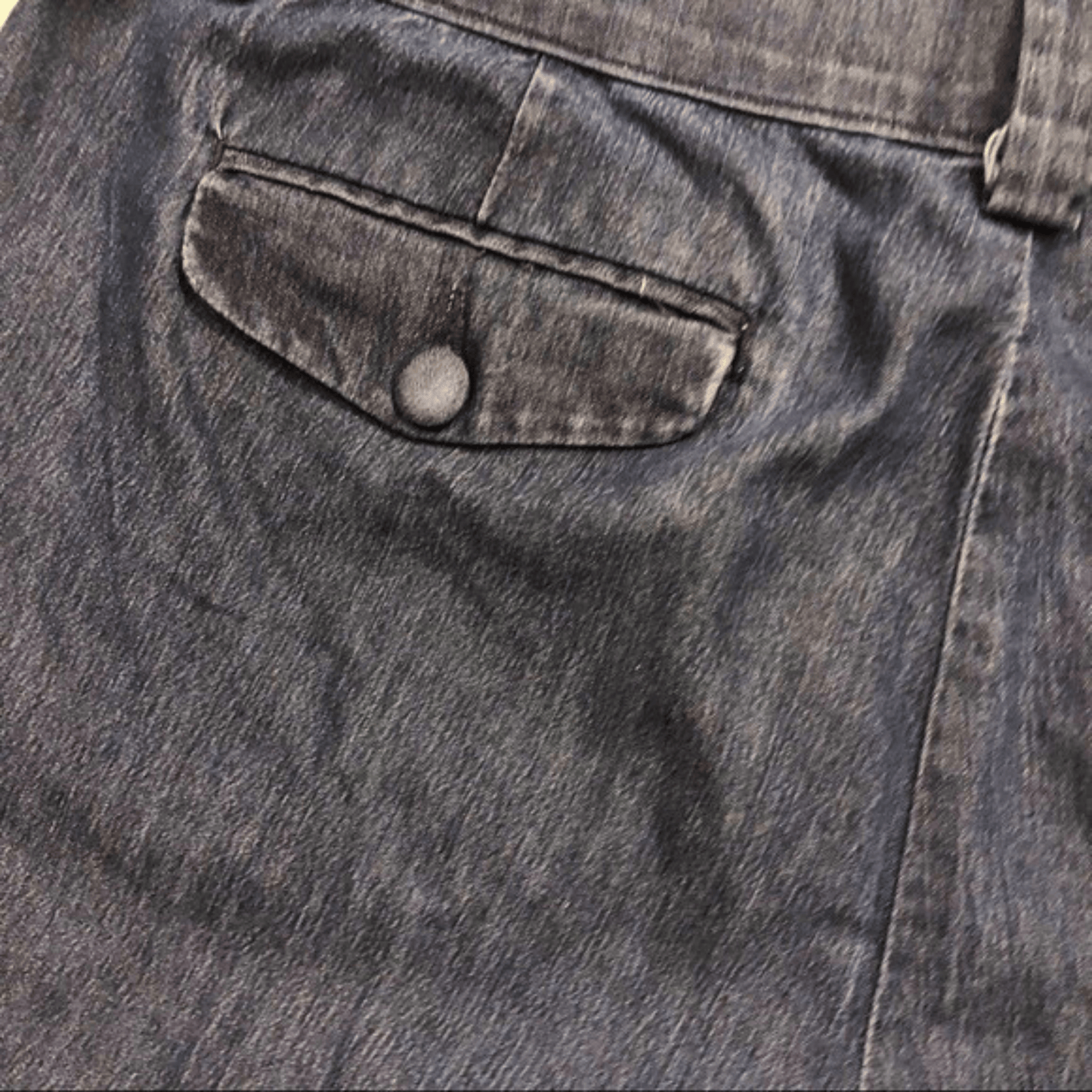 Close-up of a pocket on a denim jacket with a button.