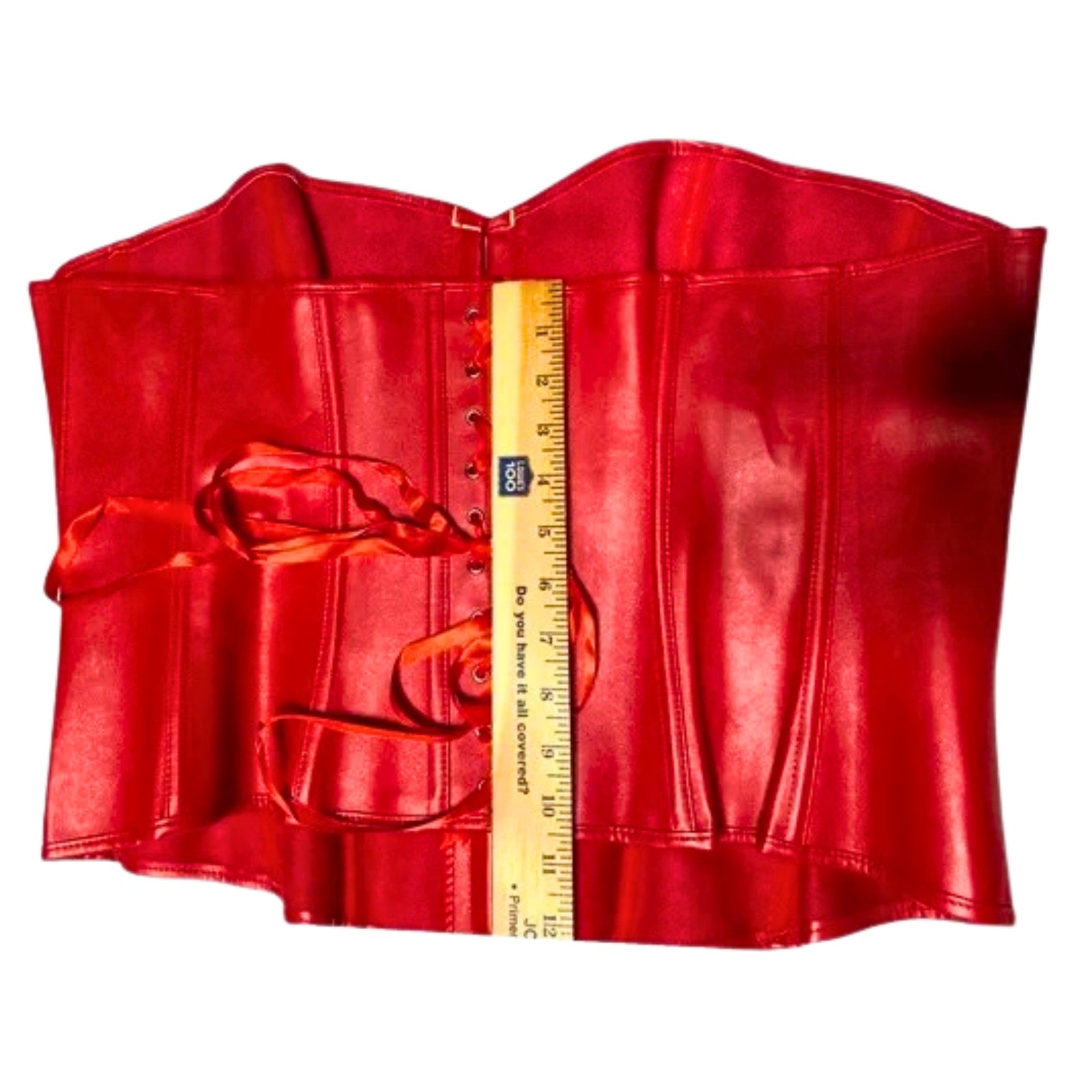 Red leather corset with a ruler for scale on a white background