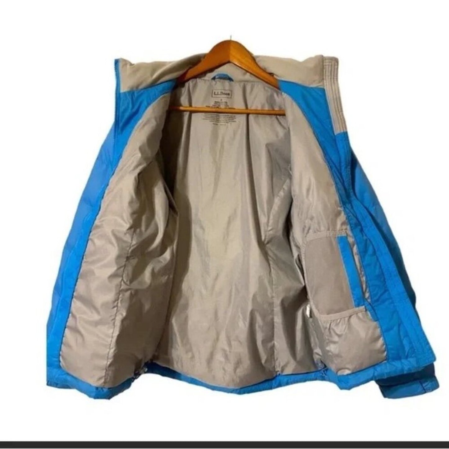 Beige and blue jacket on a hanger against a white background