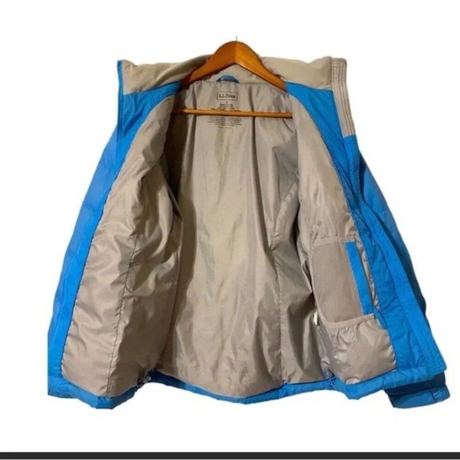 Beige and blue jacket on a hanger against a white background