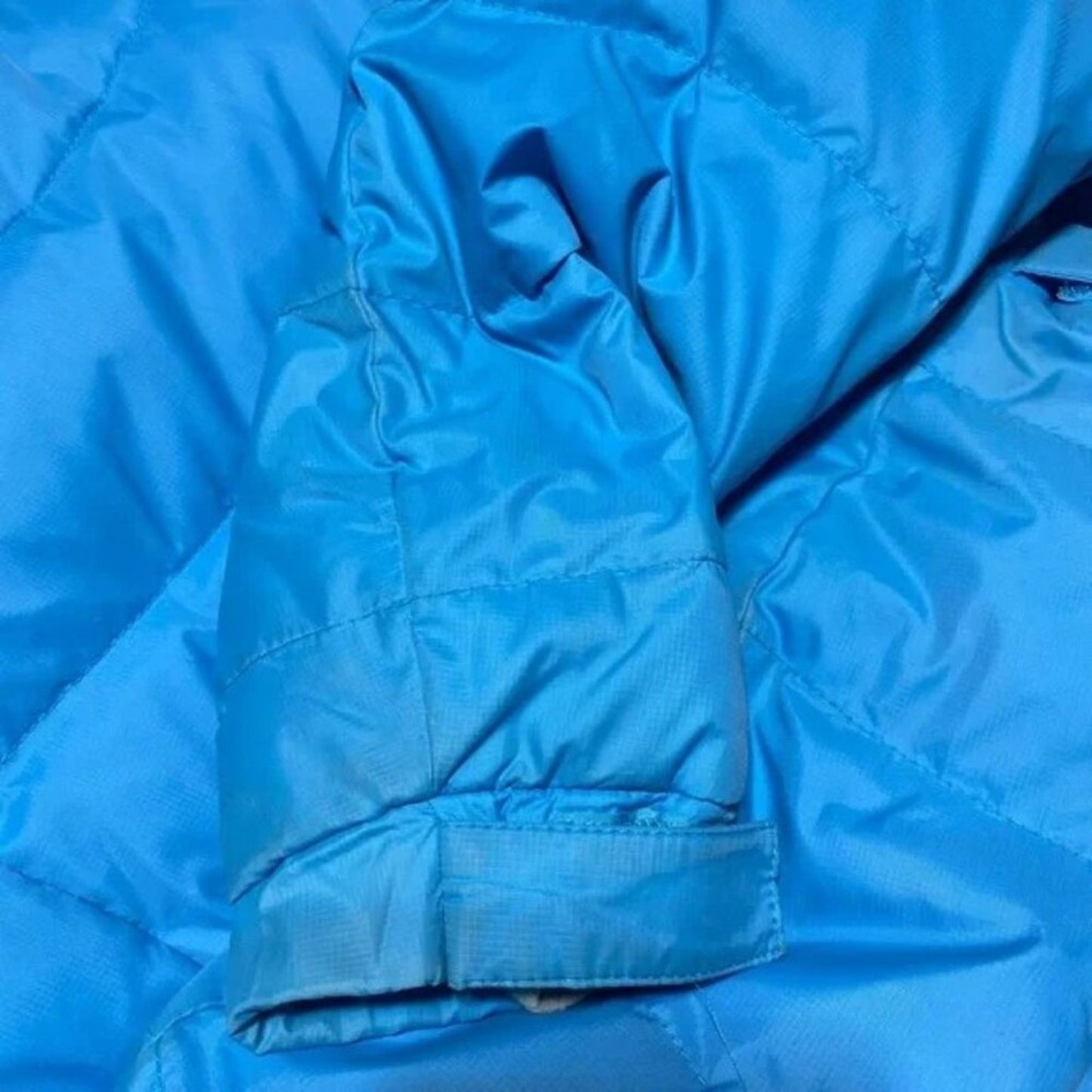 Close-up of a blue quilted jacket with visible stitching