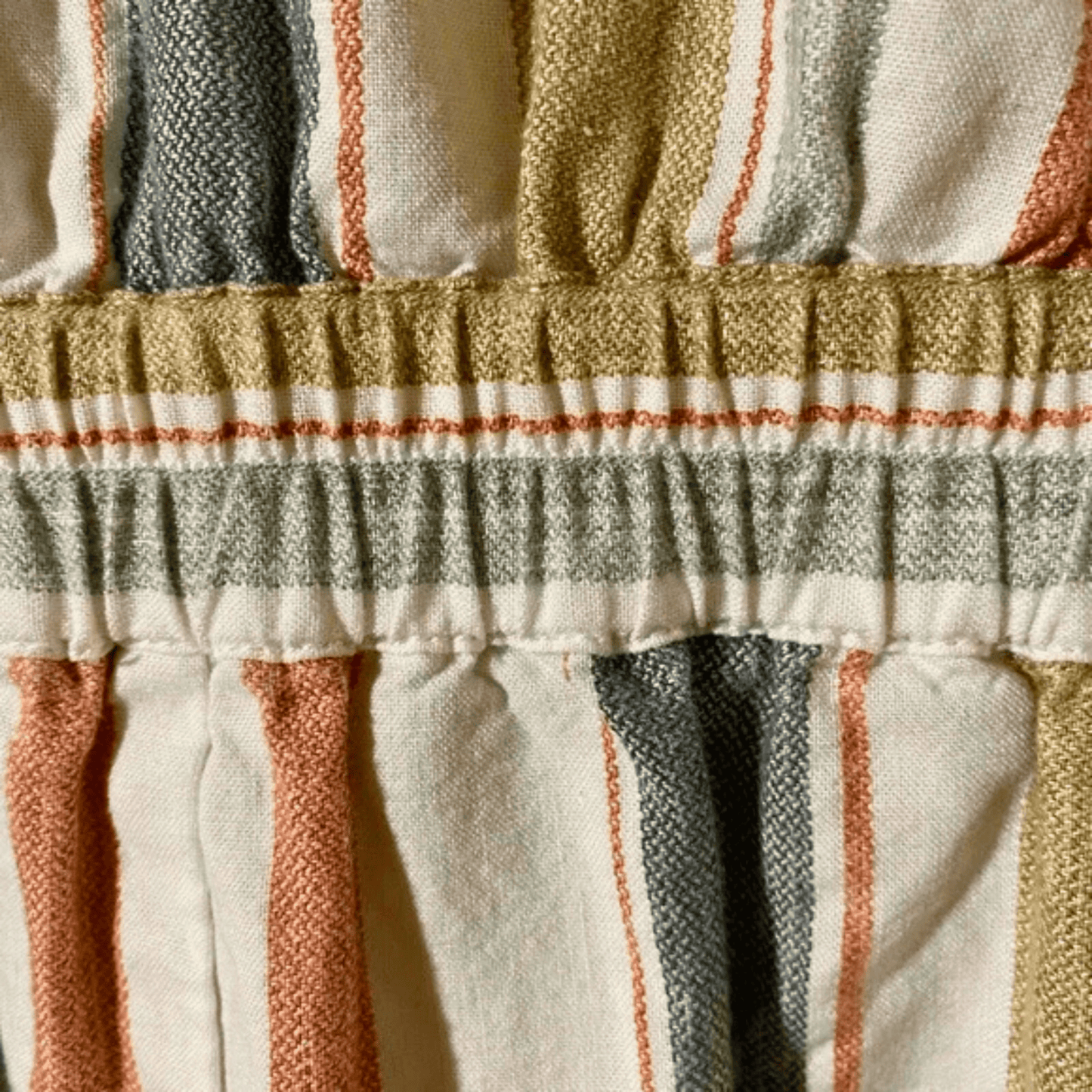 Close-up of a textured fabric with horizontal stripes in beige, brown, and gray.