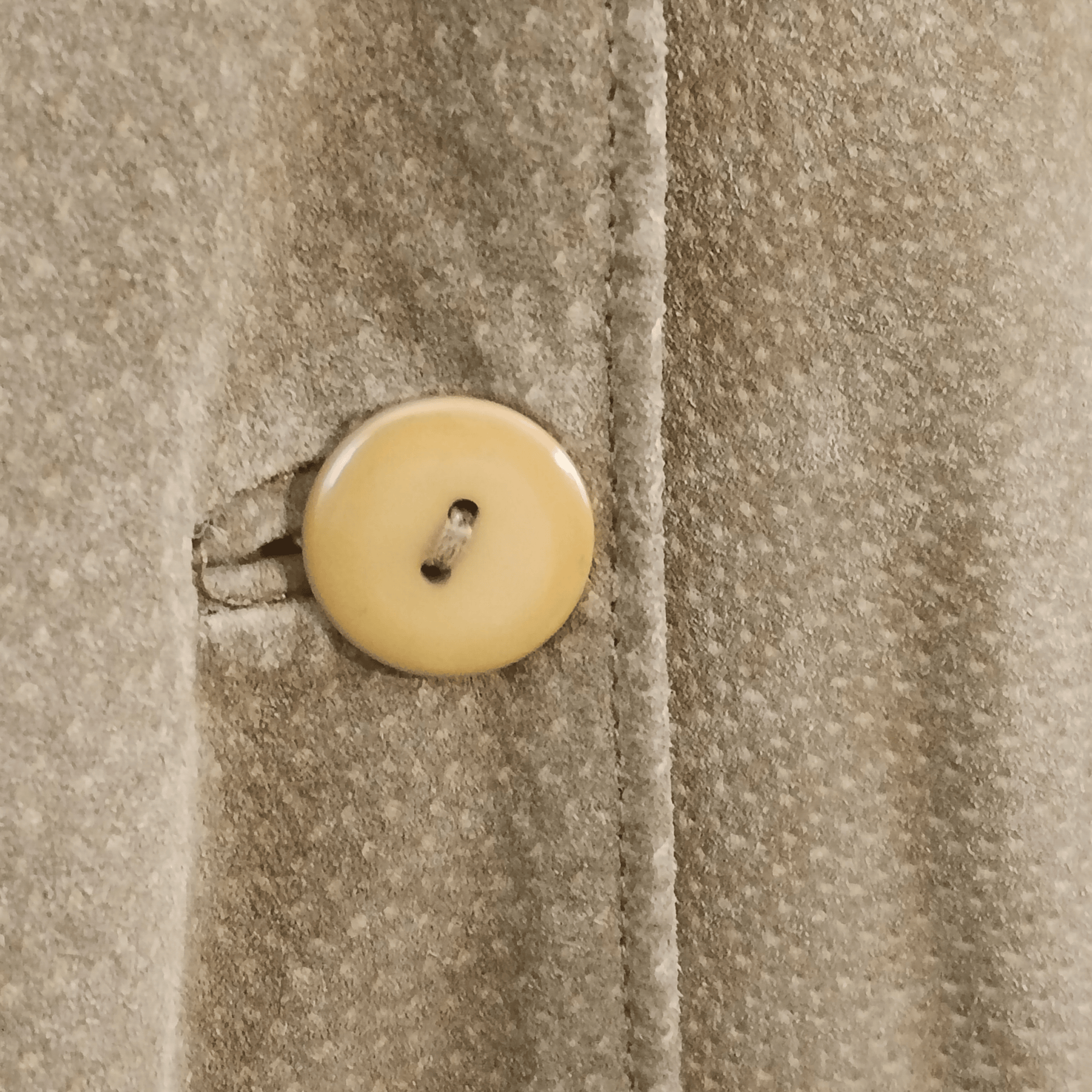 Close-up of a beige button on a textured fabric background