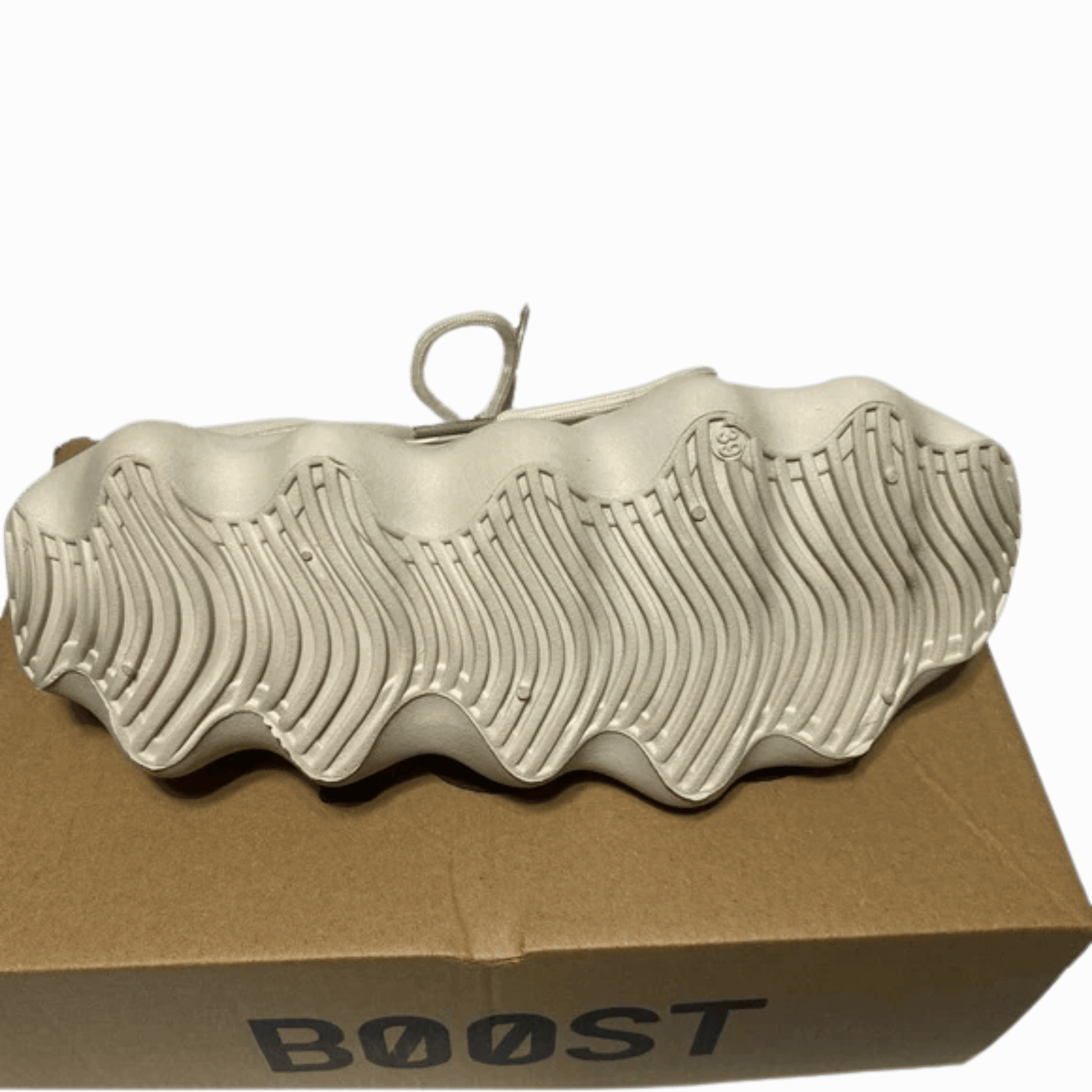 White sneaker with 'Boost' sole on a cardboard box against a dark background