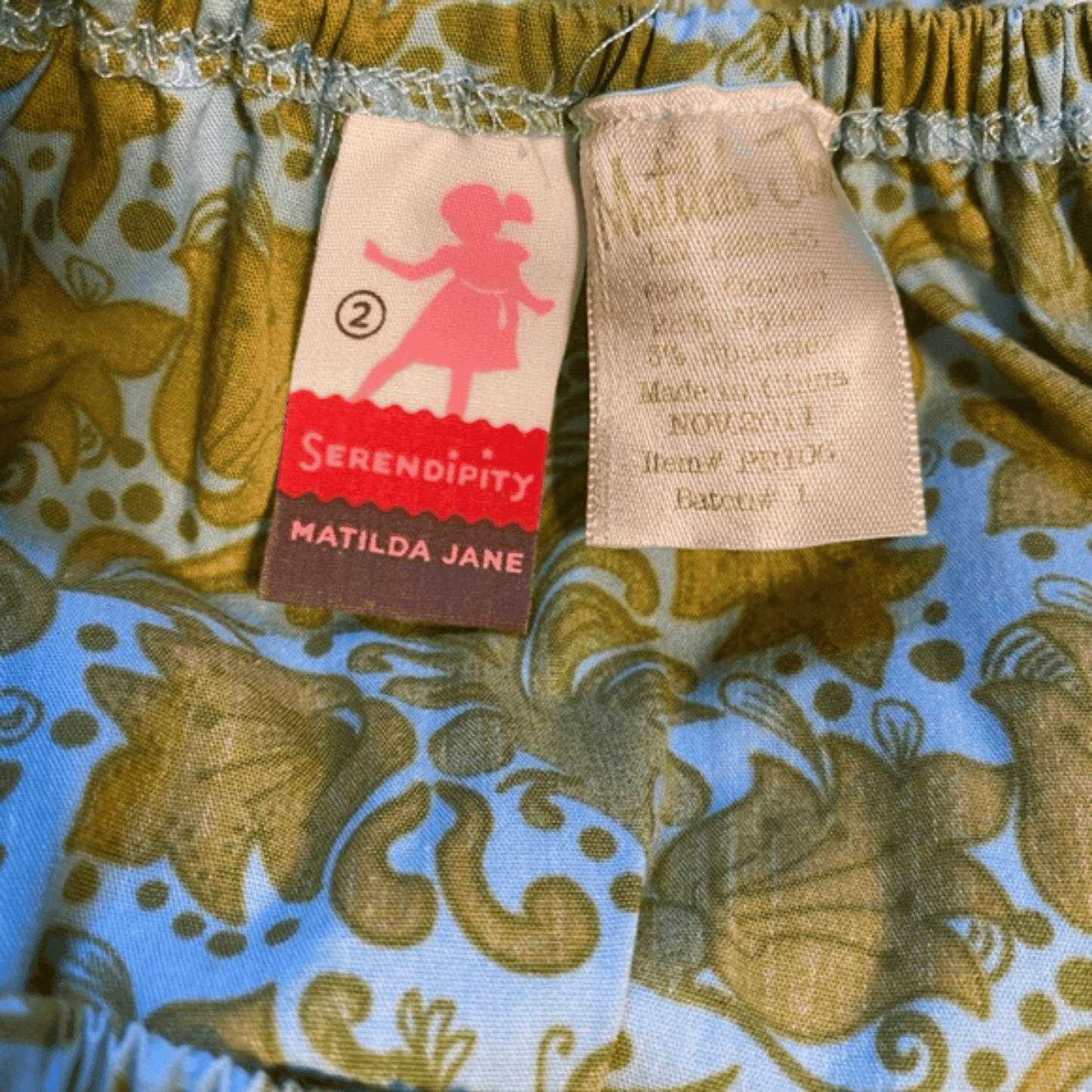 Close-up of a Matilda Jane dress with brand labels on a floral patterned fabric.